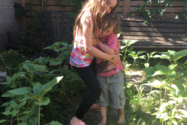 Girl and small boy (siblings) hug.